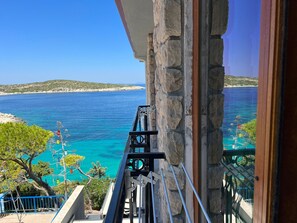 A balcony with a stone wall and a view of the sea.