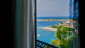 Une vue sur la côte depuis un balcon doté d’une balustrade, avec un ciel dégagé et des bâtiments le long du littoral.