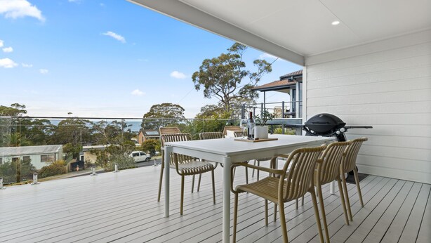 Un balcon avec une table et des chaises, un barbecue et une vue sur les environs.