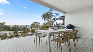 Un balcon avec une table et des chaises, un barbecue et une vue sur les environs.