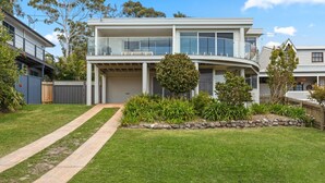 Une maison moderne à deux étages, dotée d’un patio couvert, d’un garage et d’un jardin paysager à l’avant.