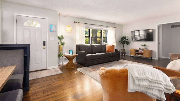 A living room with a sofa, a coffee table, a TV, and a bookshelf. - Family Fave_PutPut_Sleeps 10_Near DT LS Walkable (Lee's Summit)