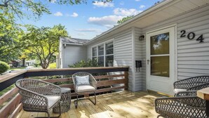 A covered outdoor deck with wicker chairs and a wooden bench. - Family Fave_PutPut_Sleeps 10_Near DT LS Walkable (Lee's Summit)