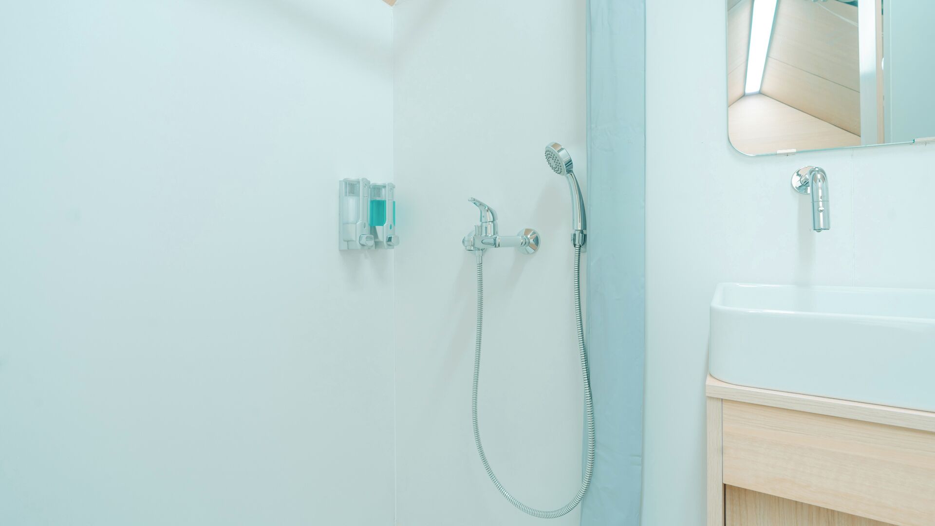 A bathroom with a shower, a sink, and a mirror.