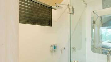Une salle de bain moderne dotée d’une douche à parois de verre, d’une porte en verre dépoli et d’une fenêtre visible.