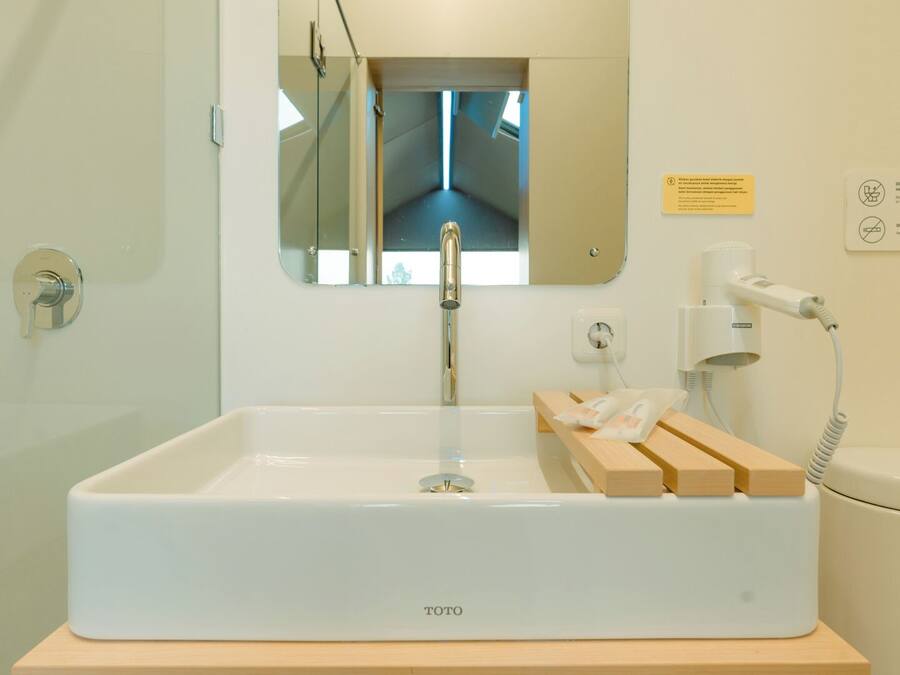 Une salle de bain avec un lavabo blanc, un miroir, une douche et des toilettes.
