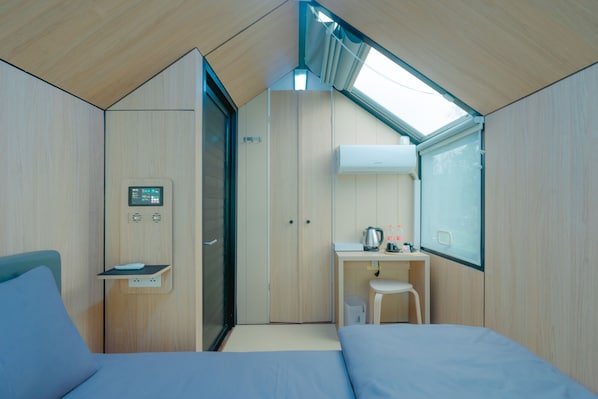 A compact, modern room with a bed, a desk, and a small kitchenette. - Bobocabin Gunung Mas (Cisarua)