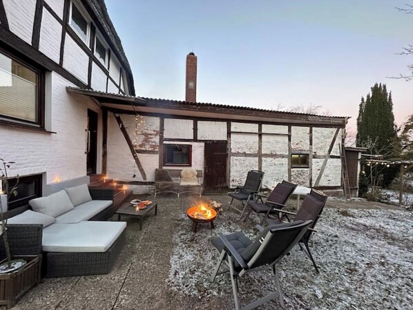 Un espace extérieur accueillant, aménagé avec un foyer, des canapés et des fauteuils.
