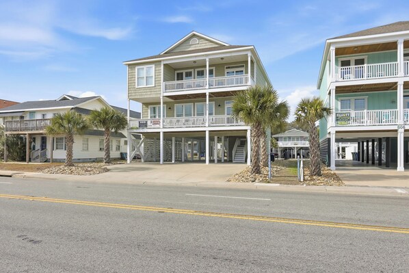 A beachfront hotel with multiple balconies, a covered walkway, and palm trees. - Anchor Down Luxury Ocean View Beach House w Pool (North Myrtle Beach)