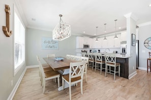 A modern kitchen with white cabinets, a central island, and pendant lighting. - Anchor Down Luxury Ocean View Beach House w Pool (North Myrtle Beach)