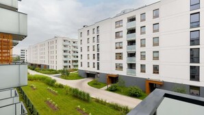 A modern apartment complex with multiple floors, balconies, and a well-maintained courtyard with pathways and greenery. - Stylish Apartment with Balcony | Air Conditioning and Parking (Warszawa)