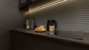 A modern kitchen with a sleek countertop, a coffee maker, a plate with croissants, and a potted plant. - Stylish Apartment with Balcony | Air Conditioning and Parking (Warszawa)
