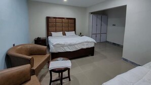 Ein Schlafzimmer mit Bett, Stuhl, Nachttisch, Deckenventilator und Kleiderschrank.