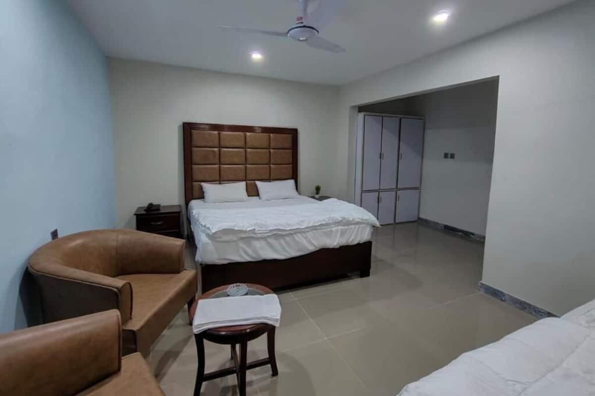 A bedroom with a bed, a chair, a nightstand, a ceiling fan, and a wardrobe.