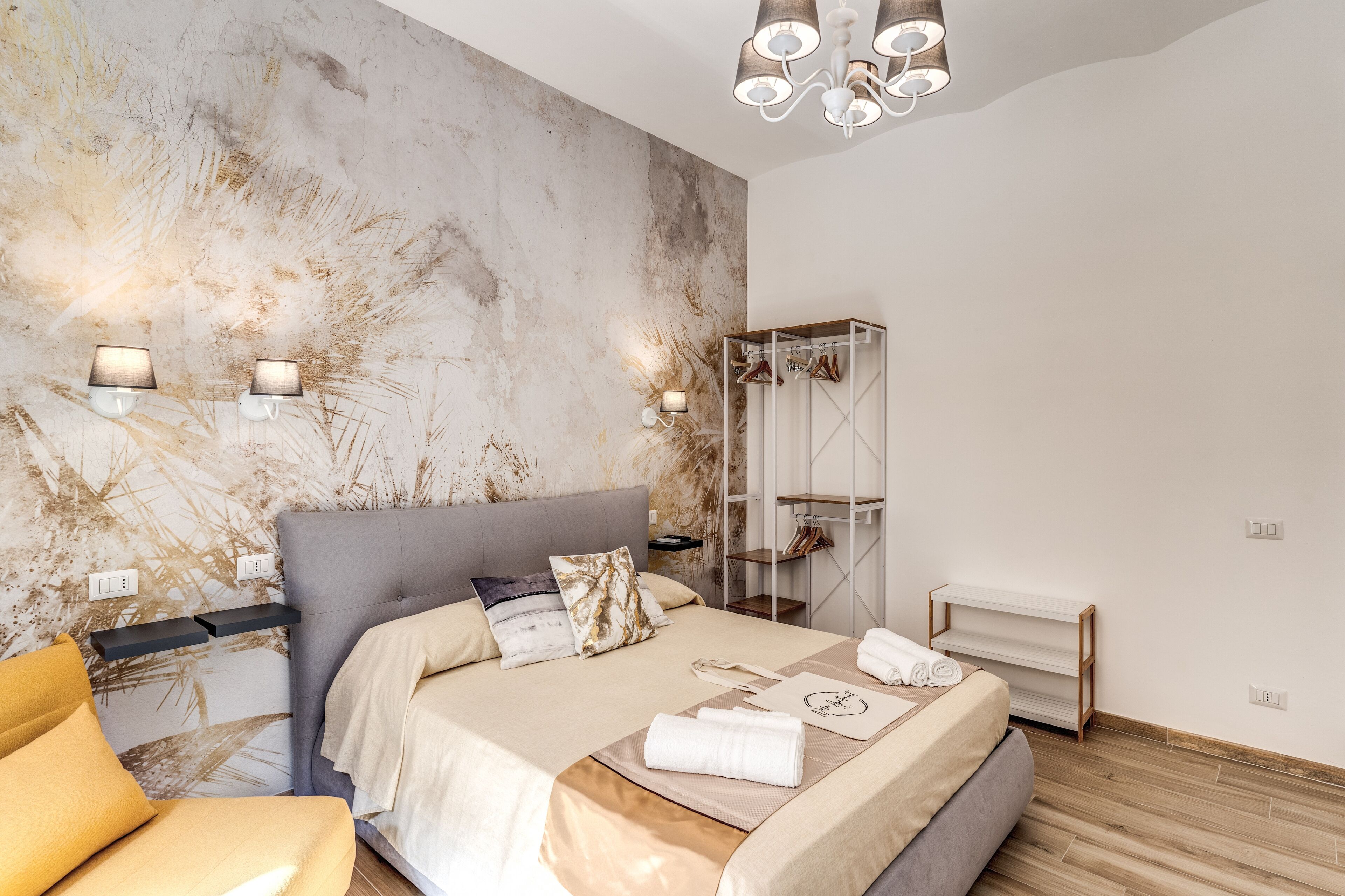A modern bedroom with a large bed, bedside lamps, a wardrobe, and a wooden floor.
