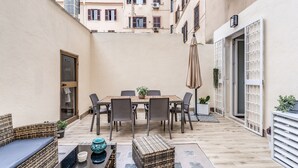 A courtyard with a dining table, chairs, a sofa, and a small table with a bowl and a vase. - New apartment in center of Rome, 300mt from the metro stop and train station (Roma)