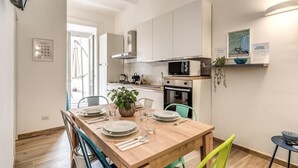 A modern kitchen with white cabinets, a wooden dining table, and a small side table. - New apartment in center of Rome, 300mt from the metro stop and train station (Roma)