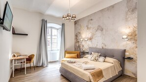 A modern bedroom with a large bed, a desk, and a TV. - New apartment in center of Rome, 300mt from the metro stop and train station (Roma)