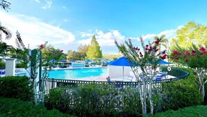 A pool area with a blue canopy, lounge chairs, and a fenced deck.