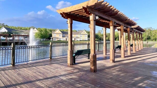 A wooden deck with a pergola structure, a fountain, and a bench.