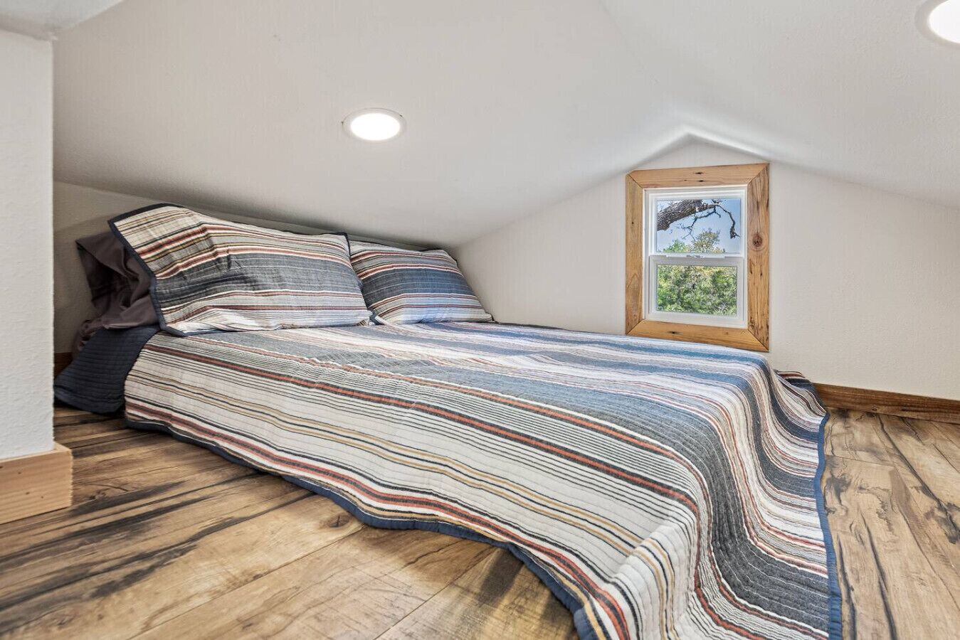 Loft with a queen bed and oak-tree views. Accessed by a rolling library ladder from the main level.