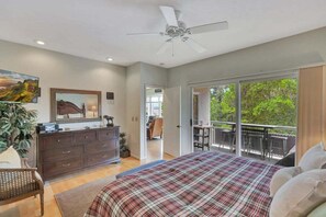 Een slaapkamer met een bed, een dressoir en een balkon met een tafel en stoelen.