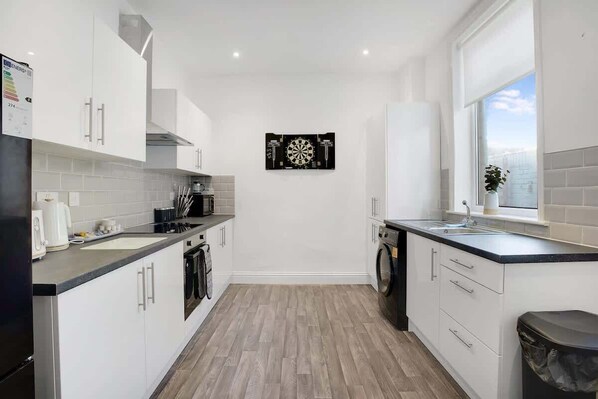 A modern kitchen with white cabinets, a black countertop, and a window with a view.