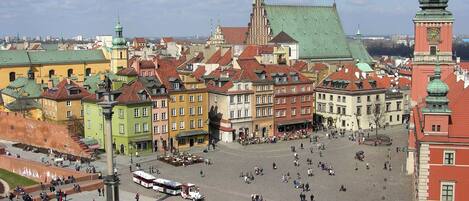 A historic square with colorful buildings, a prominent clock tower, and a tram.