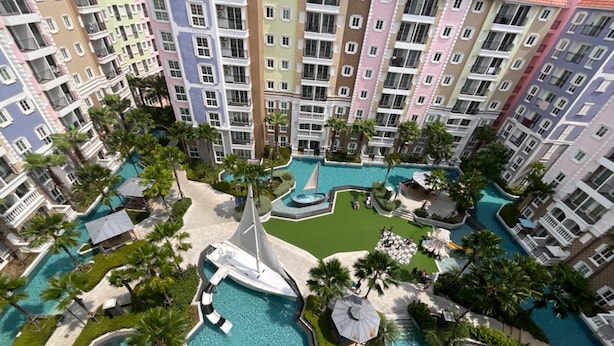 A multi-story hotel with a central swimming pool surrounded by palm trees and lounge areas. - Seven Seas Côte d'Azur by PSR (Sattahip)