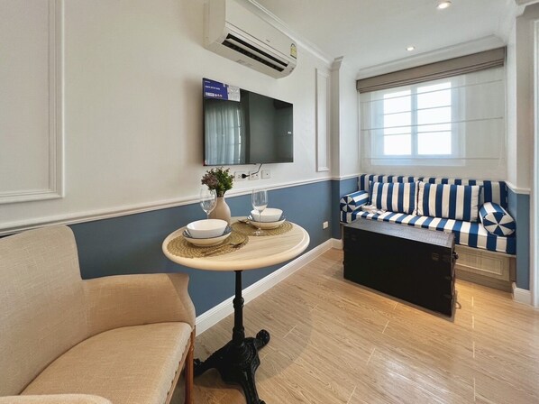 A modern living room with a beige sofa, a striped sofa, a round coffee table with decorative bowls, and a mounted TV.
