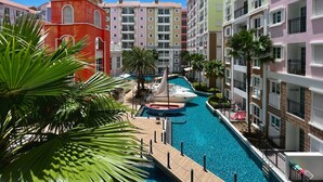 A hotel with a swimming pool, palm trees, and colorful buildings. - Seven Seas Côte d'Azur by PSR (Sattahip)