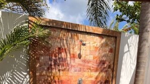 A brick wall with a circular cutout at the base, a metal handle, and a small bird perched on the wall. - Exlusive Lodge in a Boutique Hotel (Selong Belanak)