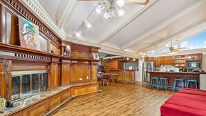 A spacious kitchen with wooden cabinetry, a large island, and a red cushioned seating area. - Enormous Historic Treme Pad by French Quarter (New Orleans)