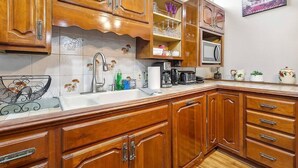 A kitchen with wooden cabinets, a sink, and various kitchen appliances. - Enormous Historic Treme Pad by French Quarter (New Orleans)