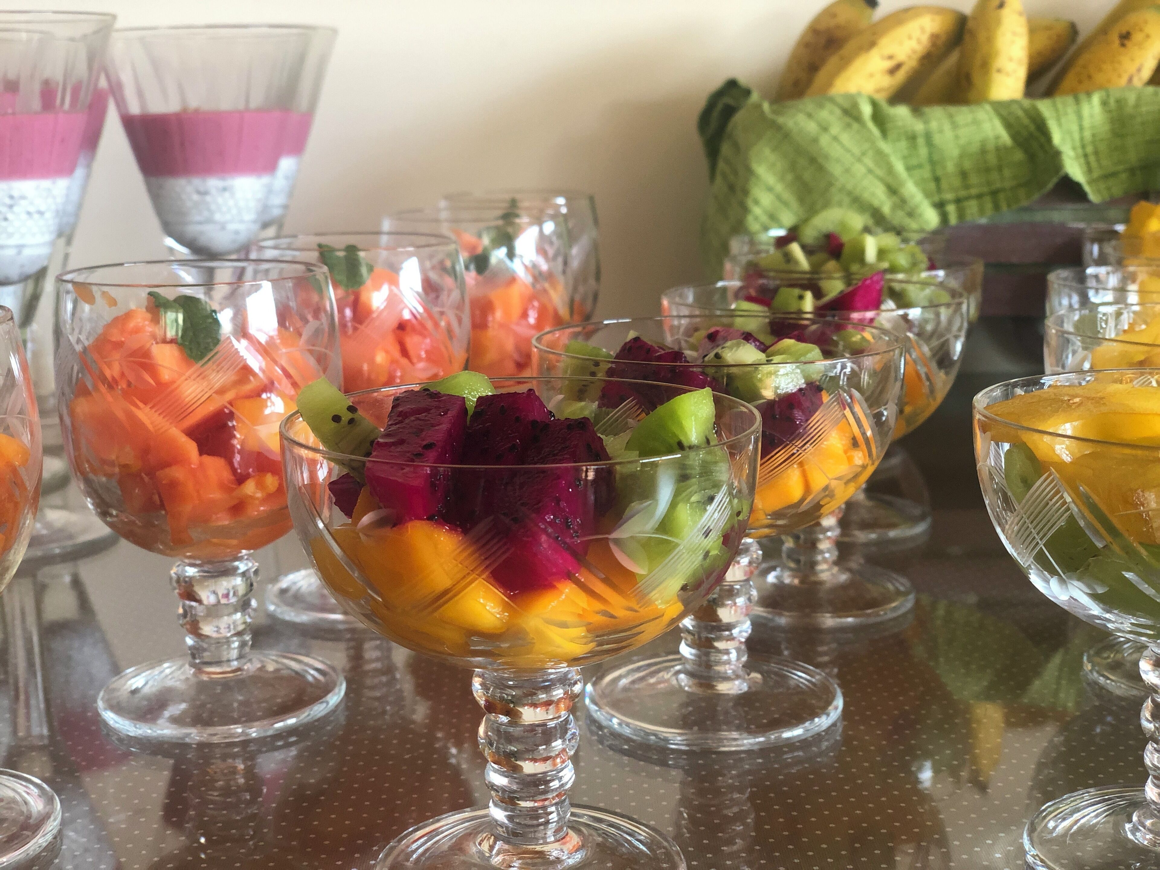 Variedad de ensaladas de fruta en cuencos de vidrio transparente sobre una mesa.