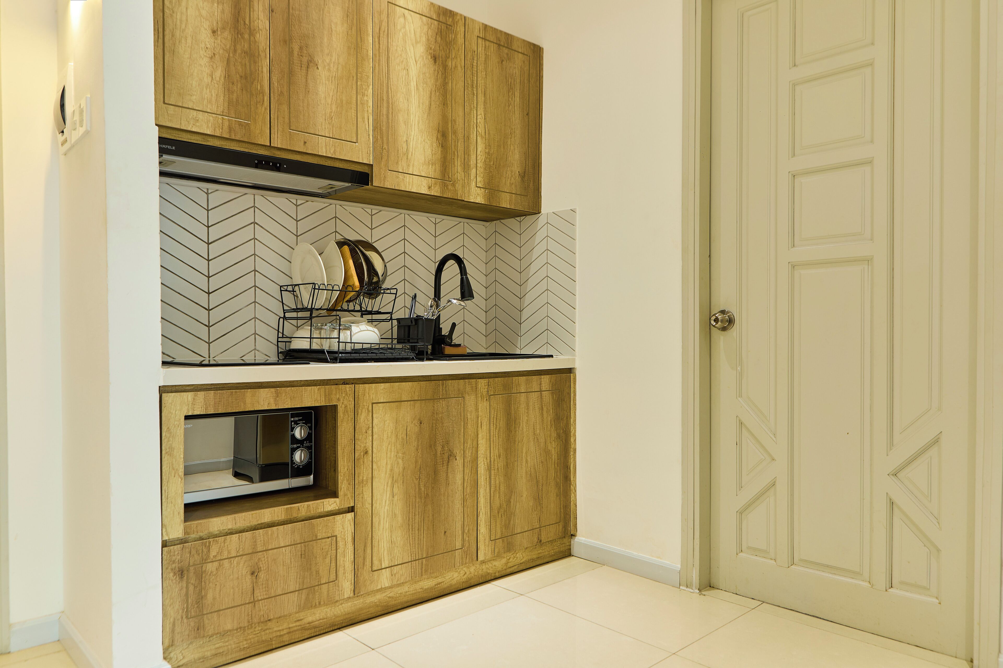 Une cuisine compacte avec des meubles en bois, un four à micro-ondes et un dosseret décoré d’un motif en chevrons.