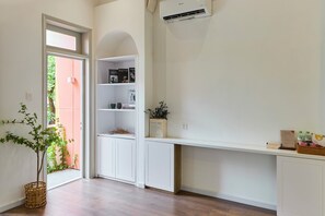 Um interior moderno com armários brancos, uma estante com revistas e uma cesta de vime com uma planta.
