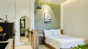 A modern hotel room with a large bed, a wooden nightstand, a desk with a computer, and a mirror. - Kin Wander Tan Quy (Ho Chi Minh City)