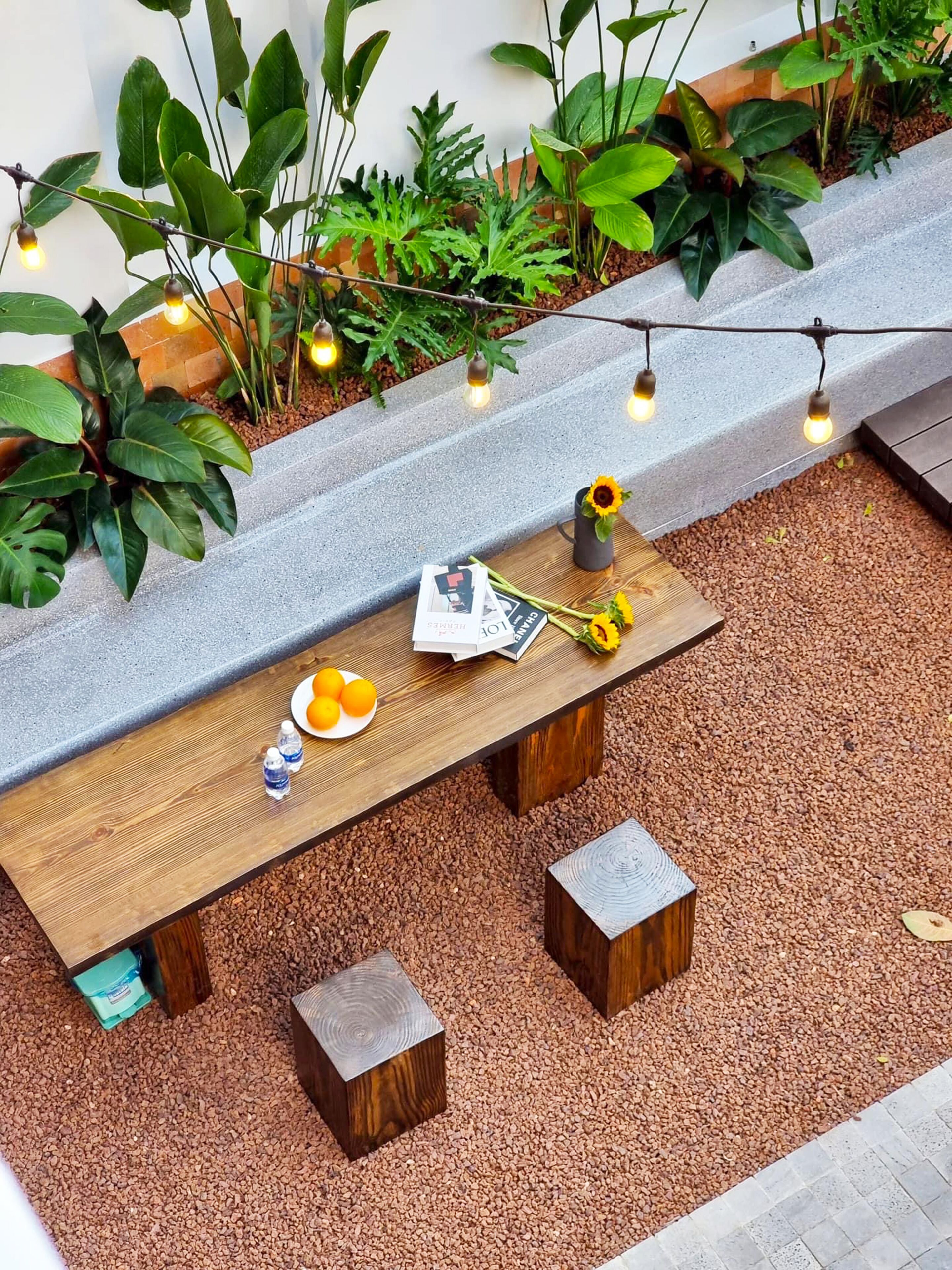 Een houten bank met een tafel, omgeven door planten en lichtjes.