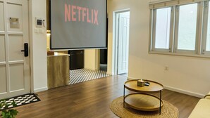 A modern living room with a large flat-screen TV mounted on the wall, a wooden coffee table, and a sofa. - Kin Wander Tan Quy (Ho Chi Minh City)