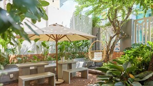 An outdoor seating area with a concrete table and benches, surrounded by lush greenery and a tree. - Kin Wander Tan Quy (Ho Chi Minh City)