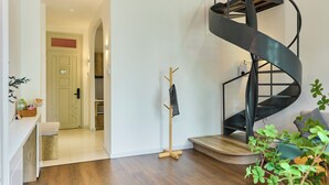 A modern interior with a spiral staircase, a wooden floor, and a small seating area. - Kin Wander Tan Quy (Ho Chi Minh City)