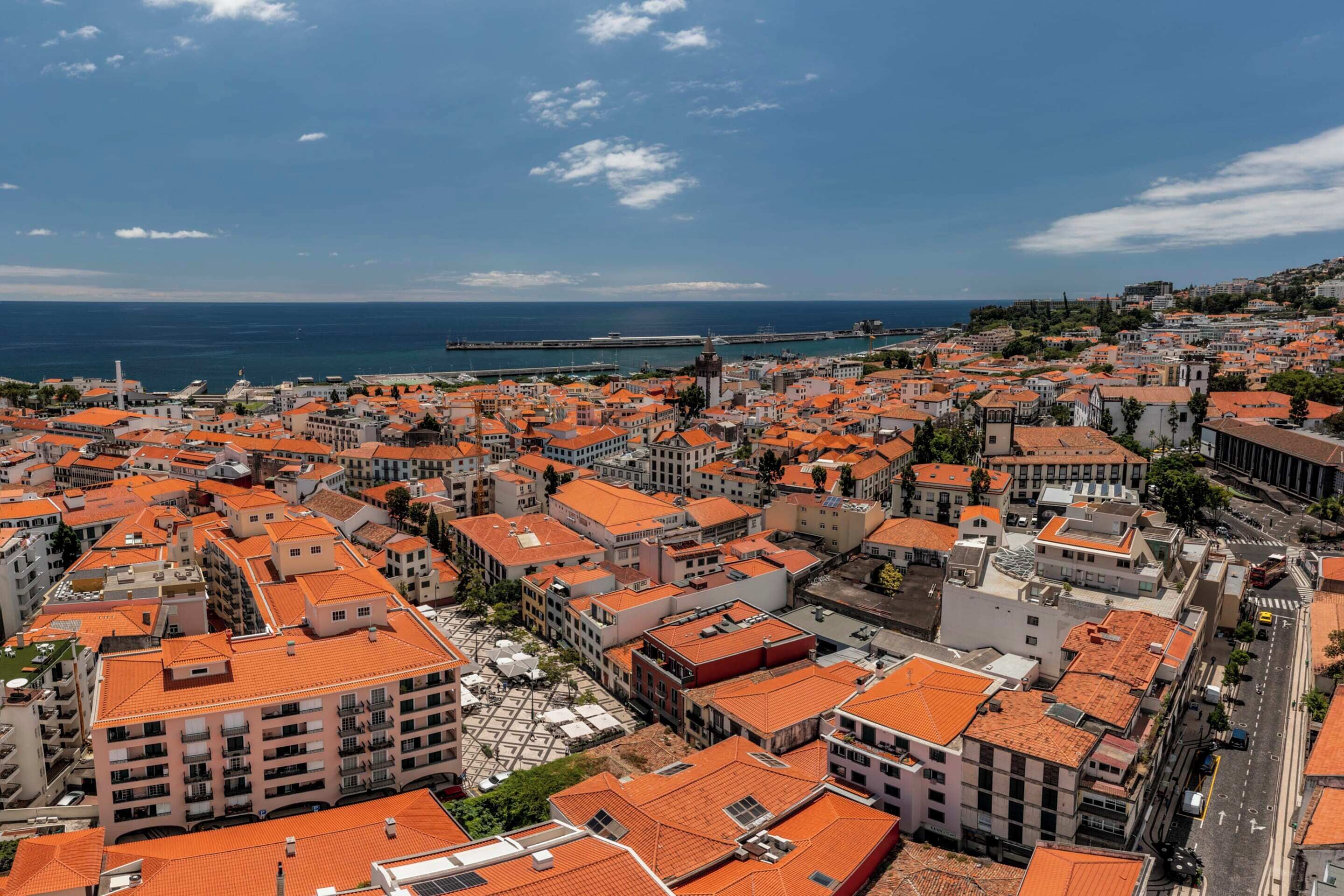 A coastal cityscape with densely packed buildings, a prominent tower, and a clear view of the sea.