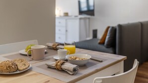 Une table de petit-déjeuner avec une assiette de toasts, un bol de céréales, une tasse et un verre de jus d’orange.