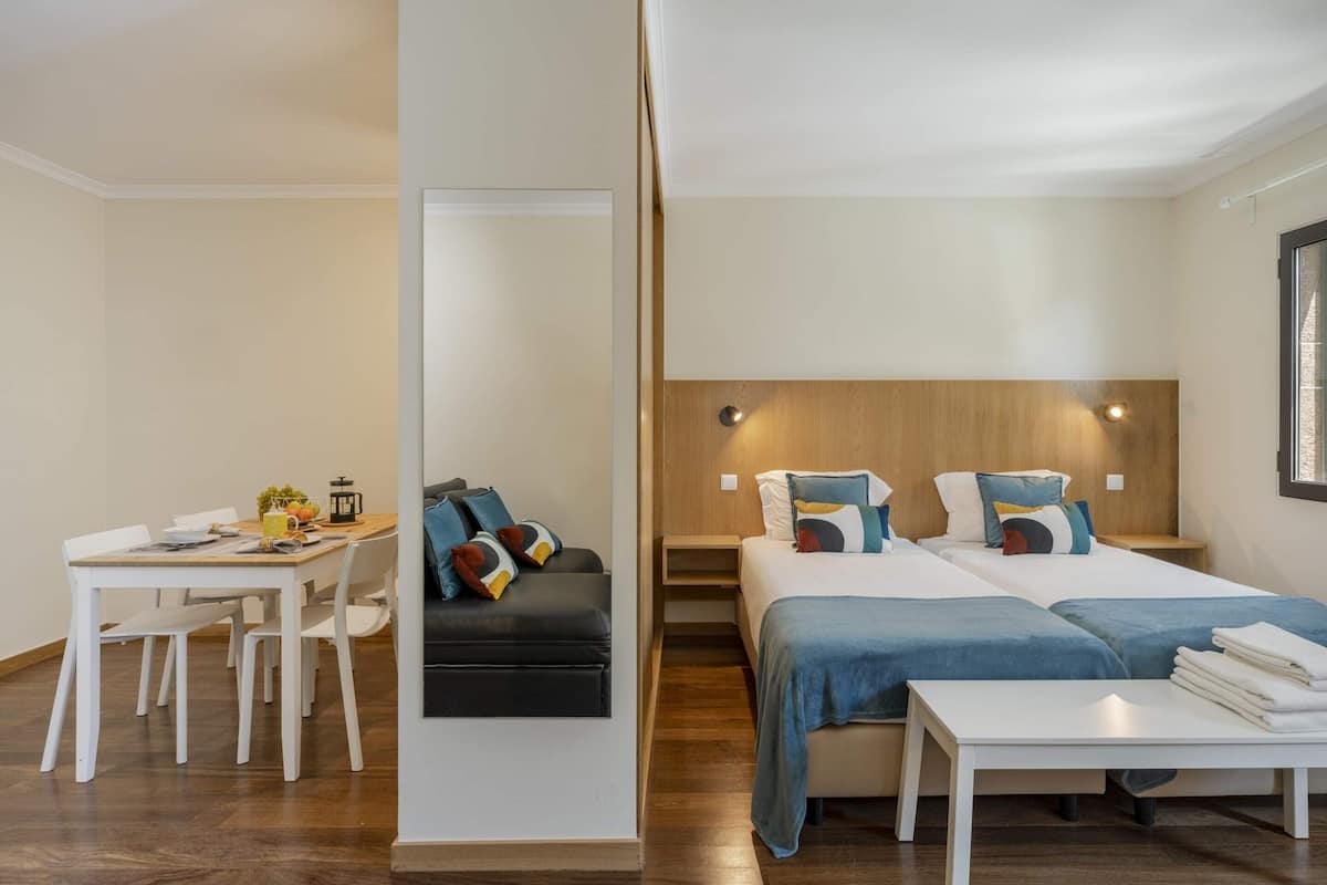Une chambre d’hôtel moderne comprenant un coin repas, un canapé, deux lits et une petite table.