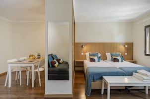 Une chambre d’hôtel moderne comprenant un coin repas, un canapé, deux lits et une petite table.