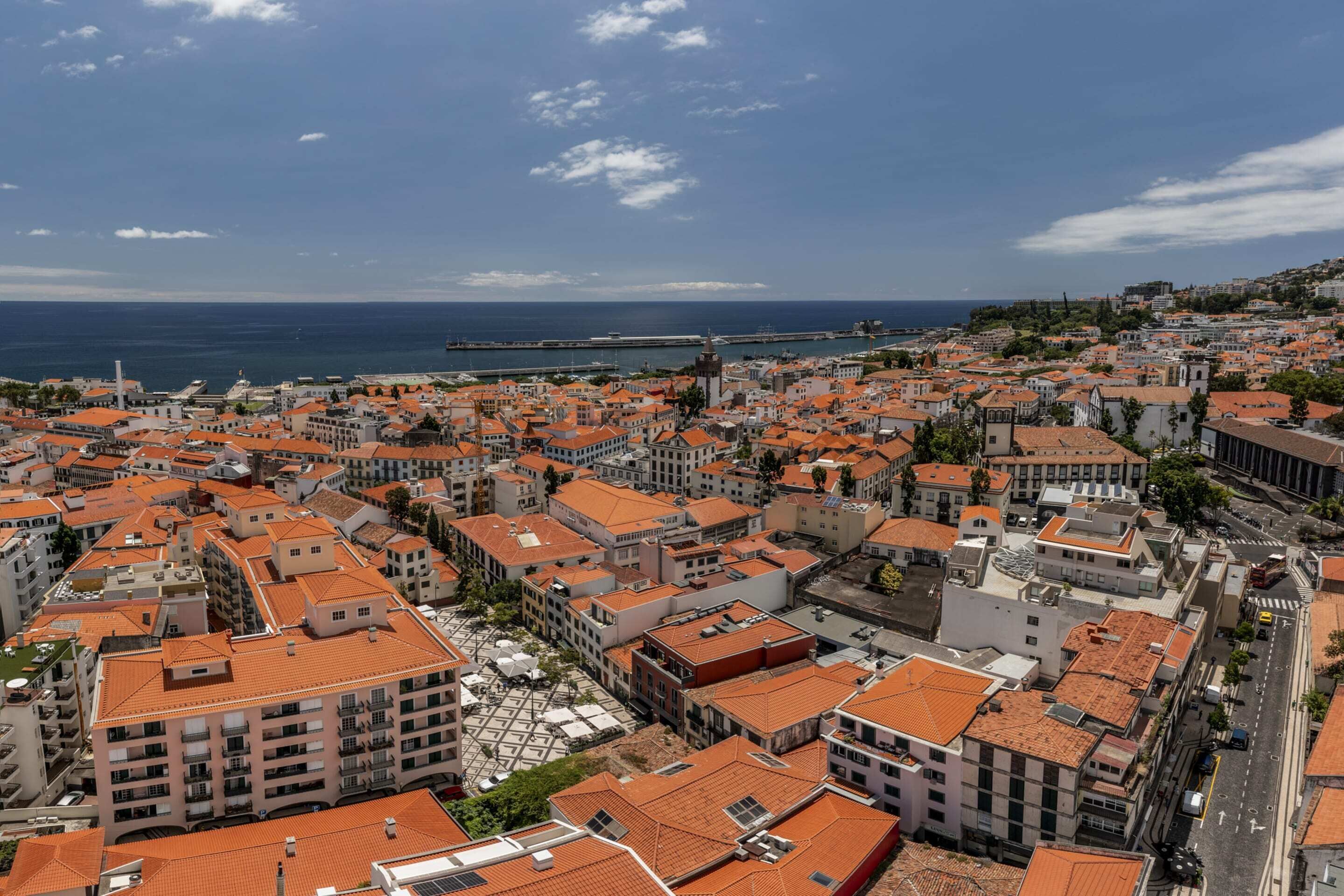 A coastal cityscape with densely packed buildings, a prominent tower, and a clear view of the sea.