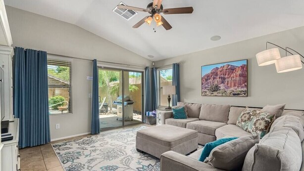 A spacious living room with a large sofa, a ceiling fan, and a painting of a desert landscape. - Serenity Haven with Private Pool in Gilbert (Gilbert)