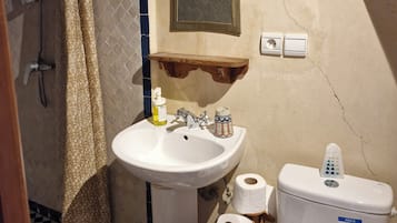 Et badeværelse med hvid vask, spejl, toilet og badeforhæng.