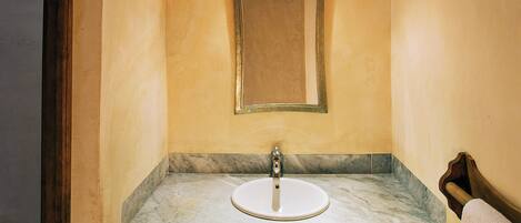 A bathroom with a wooden ceiling, a marble sink, and a checkered floor pattern.